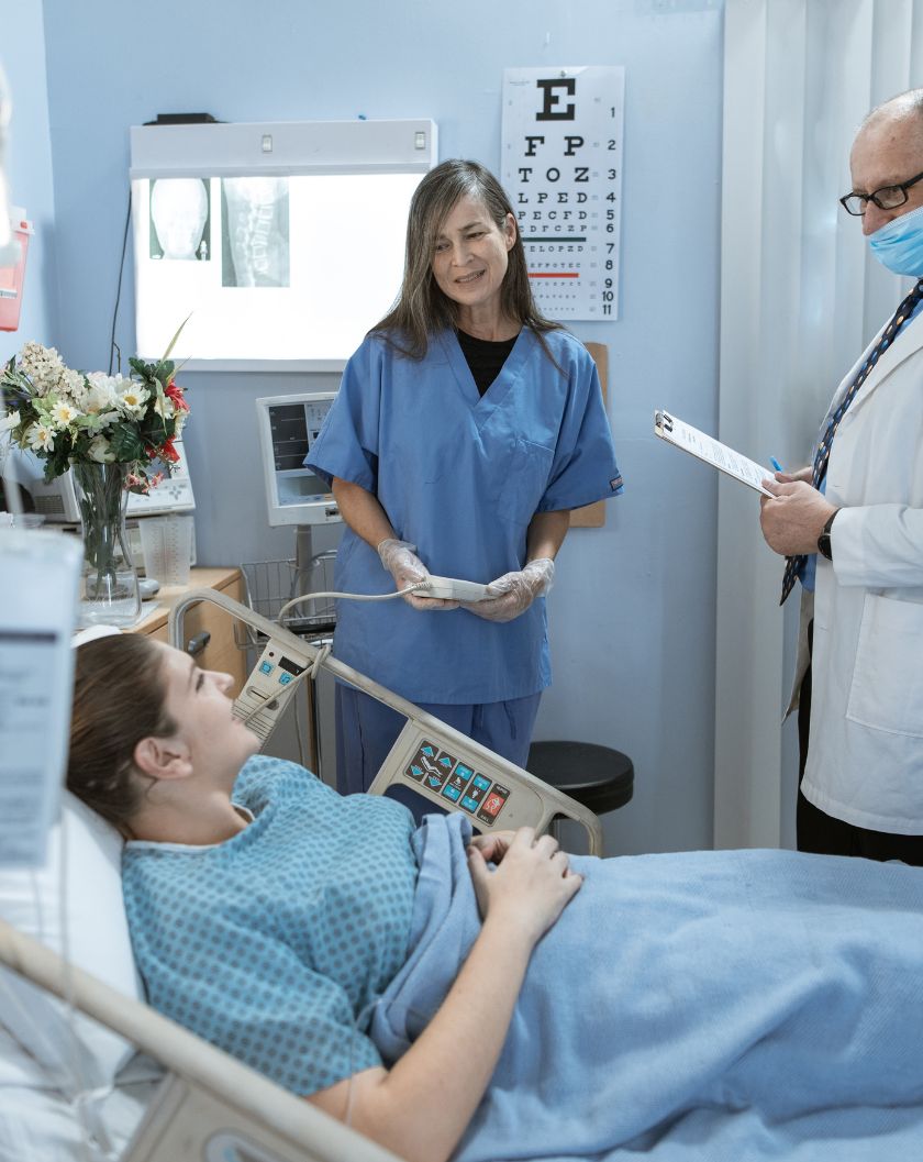 patient in hospital bed with two doctors