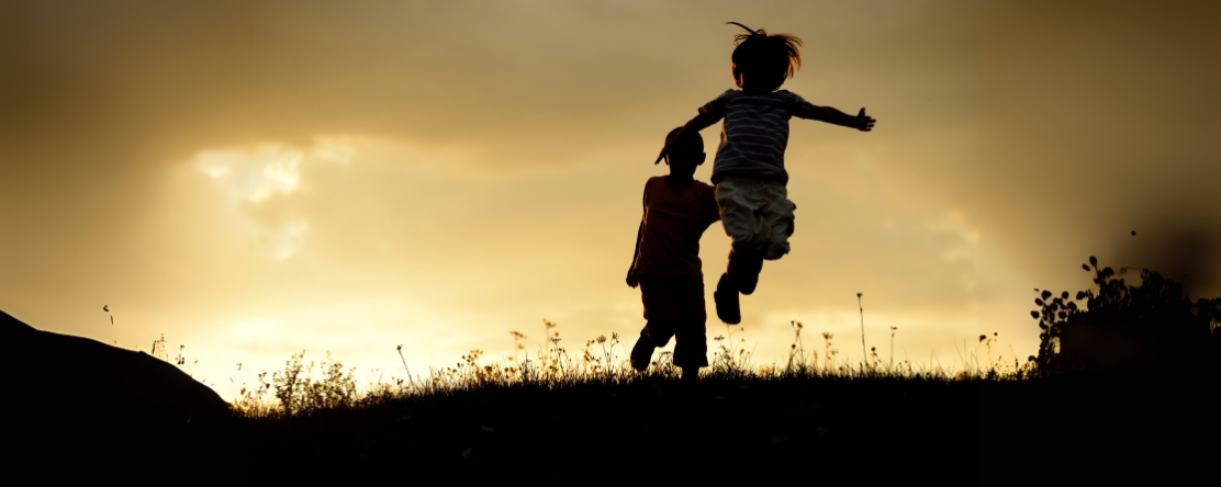 silhouette of children playing outdoors on grass