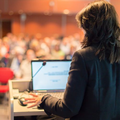 female lecturing behind podium