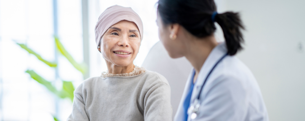older person wearing head covering sits with a physician