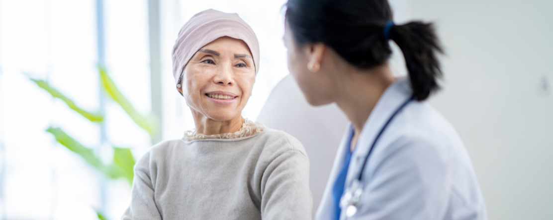 older person wearing head covering sits with a physician